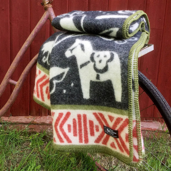 En närbild på en mjukt draperad filt med ett grafiskt mönster i vitt och brunt. Filten är vikt så att dess tunga fall och vävda struktur framhävs.